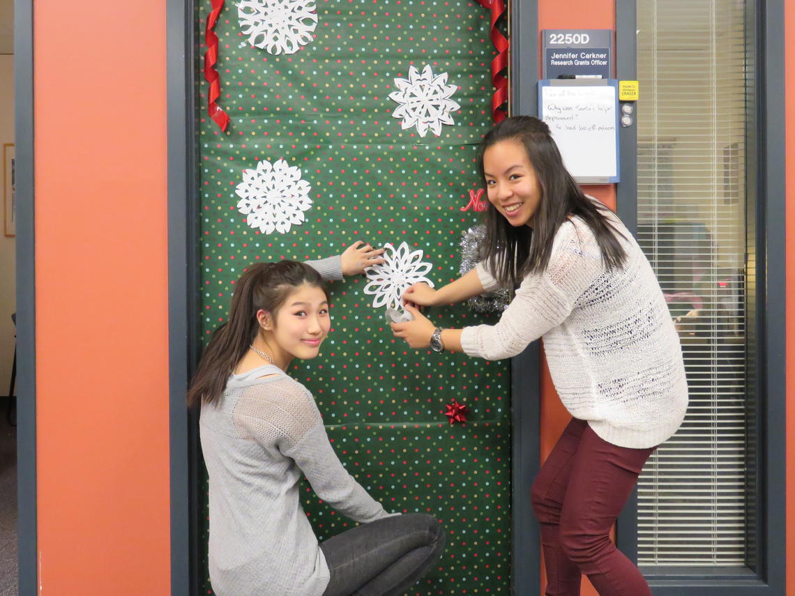 Edith (left) and Leslie, both second-year students, decorating faculty doors for the holidays.