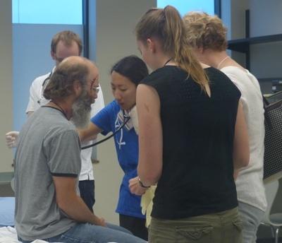 Members of an interprofessional health-care team assess and administer to a patient with simulated injuries.