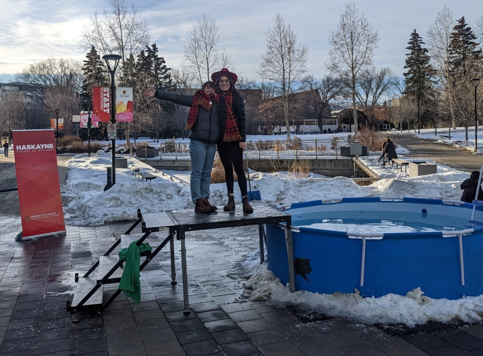 Two people standing on deck next to an icy pool situated outdoors on the UCalgary campus at the 2022 Chillin' 4 Charity event.