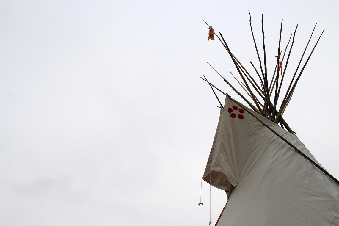 The top of a teepee against a grey sky