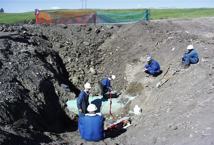 Dr. Frank Cheng and team in blue coveralls and hardhats examining a pipeline