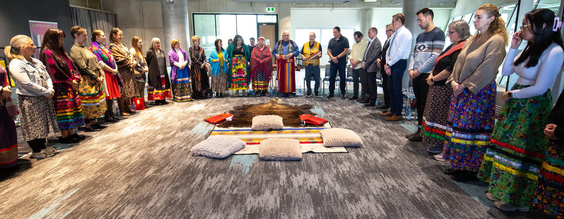 A group of people stand in a circle during an Indigenous ceremony
