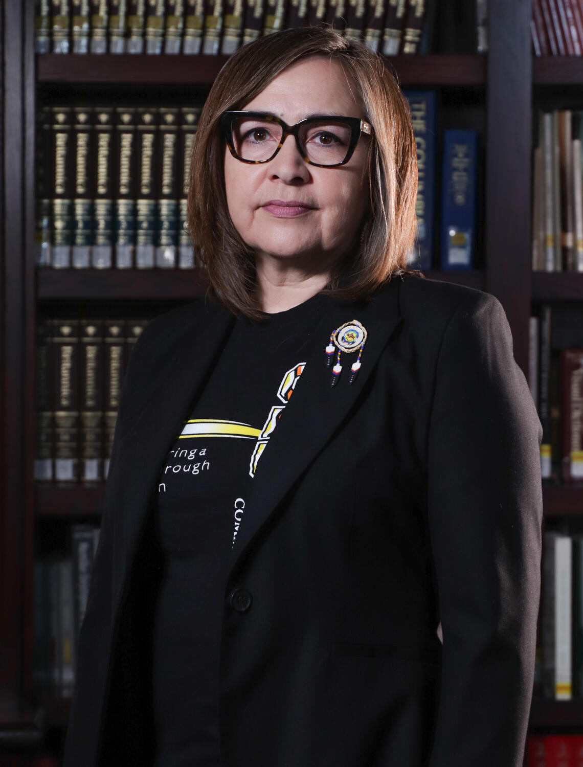 portrait of a woman in business attire, standing in front of a bookcase
