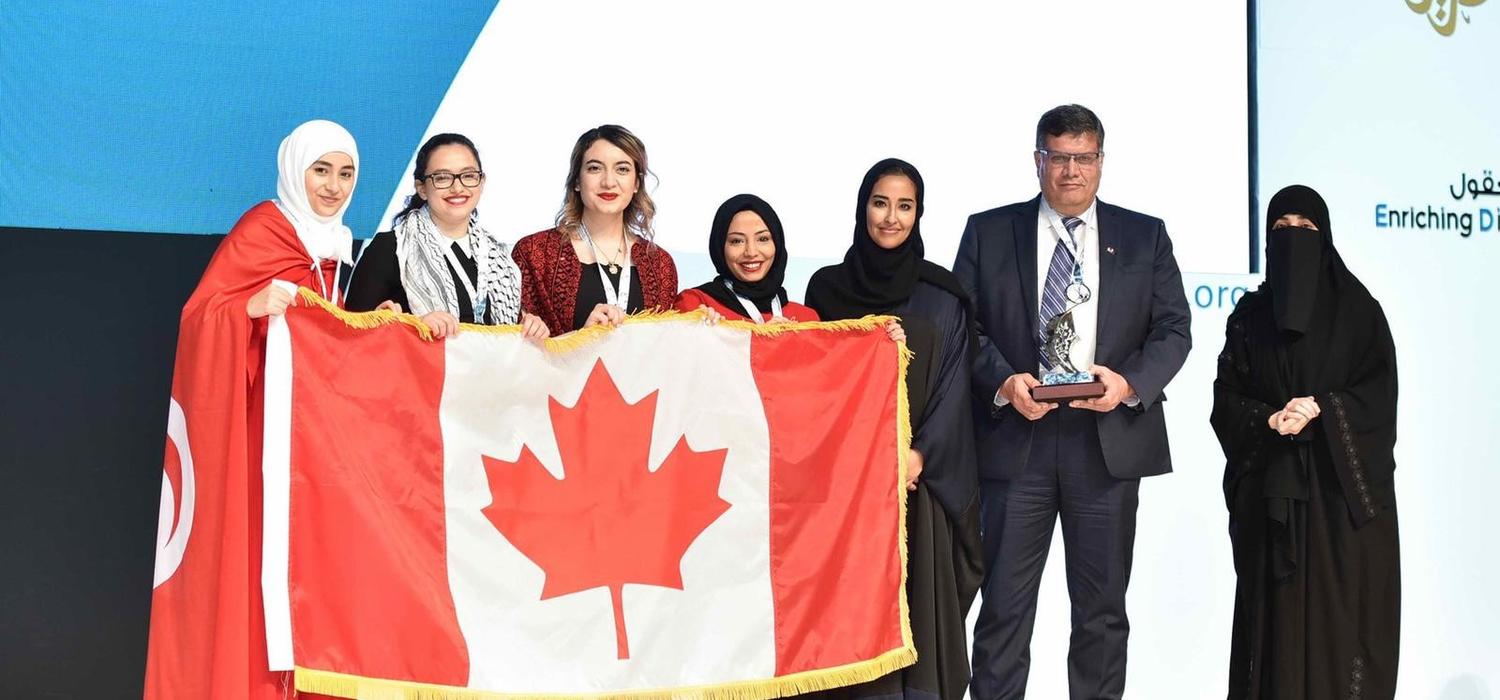 The UCalgary team accepts their silver award with a flag borrowed from the Canadian Embassy in Doha. From left: Hager Ben Mansour, Faculty of Science; Mais Abu Saleh, Faculty of Kinesiology; Rineem Saleh and Heyam Abdulrahman, Faculty of Arts; Machaille Al-Naimi, of the Qatar Foundation; Ziad Abusara, team coach from the Faculty of Kinesiology; and Hayat Abdullah Marafi, the executive director of QatarDebate. Photos courtesy Ziad Abusara