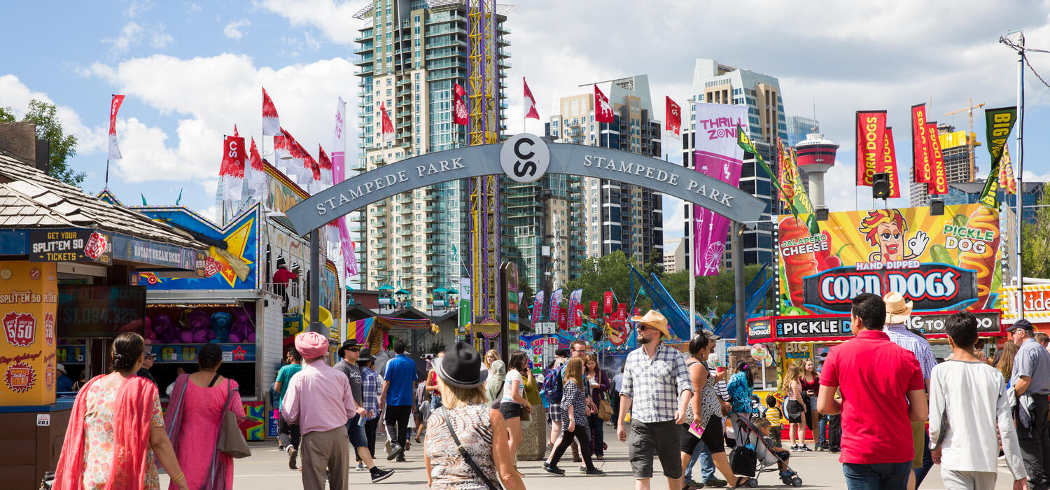 People enjoying the Stampede grounds with the city buildings in the background