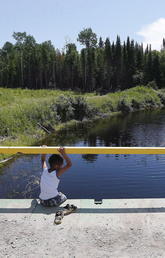 A boy sits on a bridge over a man-made channel in the First Nation of Shoal Lake 40, straddling the Manitoba/Ontario border, in June 2015. Until recently, a boil-water advisory had been in place in the community for more than 20 years despite its relative close proximity to Winnipeg