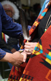 A close up shot of a feather passing at an Indigenous graduation ceremony