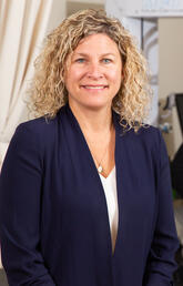 A woman smiles at the camera while an experiment goes on behind her