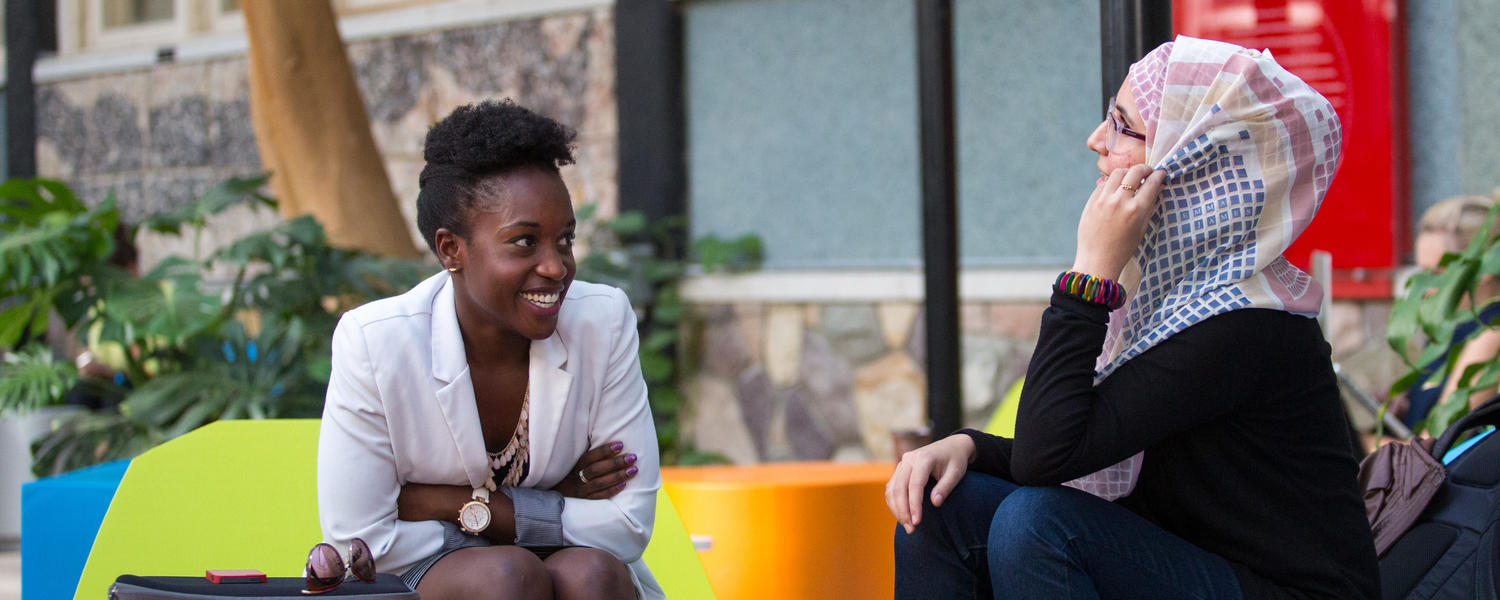 Two women talking at colourful table, UCalgary