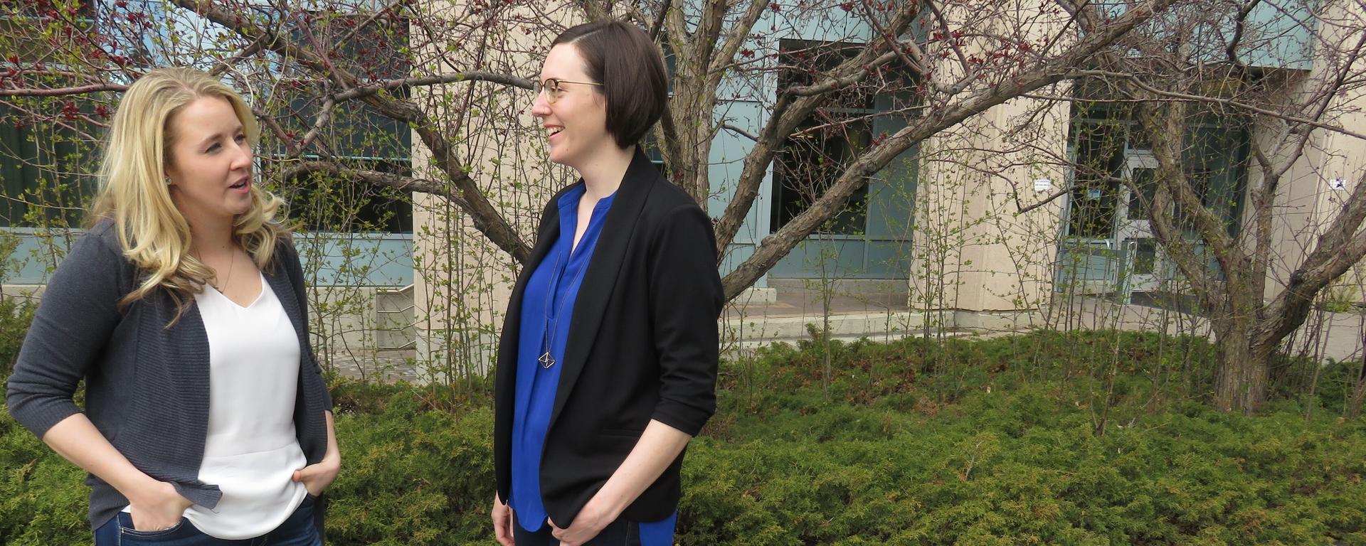 Two women talking outside of building