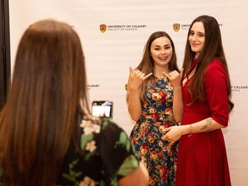 Two women posing in front of photo backdrop.
