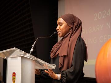 Alumni co-president speaks on stage behind podium.