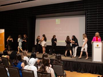Students crossing stage at pinning ceremony event.