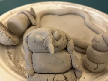 small gray clay creations, with snowman in the fore with a long nose and dread locks