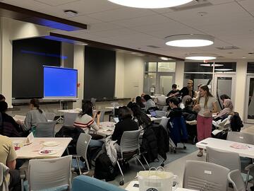 large room with people milling in front of a projector screen