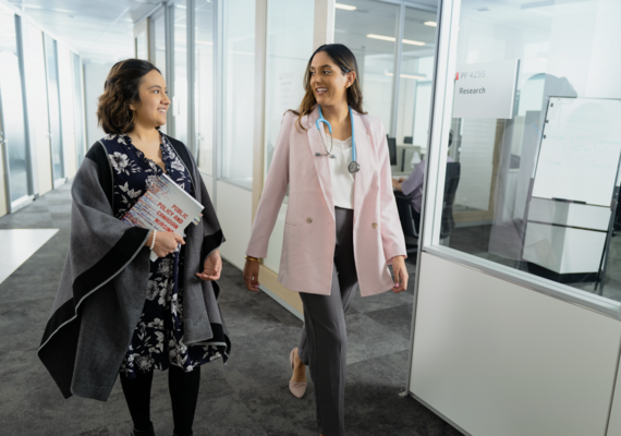 Two women walking through hallway of office