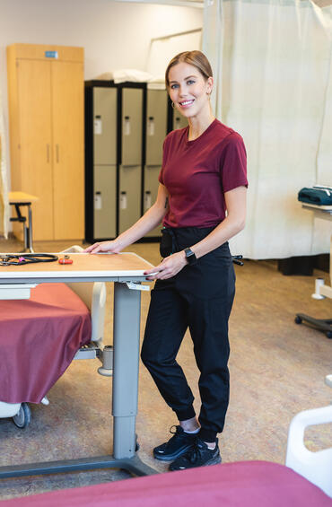 Nurse in scrubs standing at foot of bed